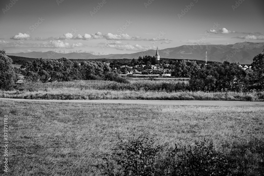 Beautiful countryside landscape of Cincu village, Brasov County, Transylvania region, Romania. Traditional transylvanian saxon village with fortified church in black & white