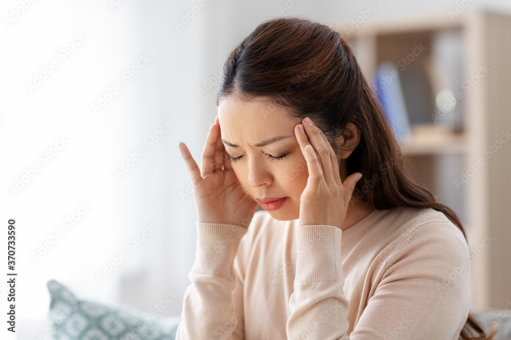 people and health problem concept - sick asian woman having headache at home people and health problem concept - sick asian woman having headache at home