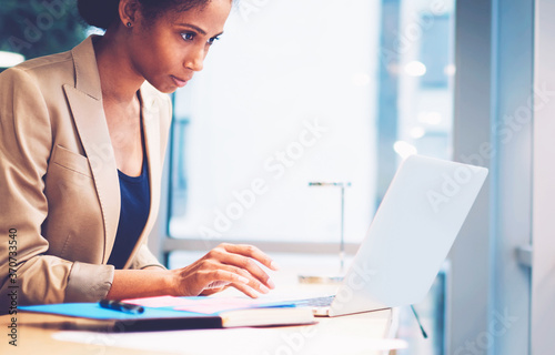 Fototapeta Concentrated afro american editor checking email box while waiting feedback from
