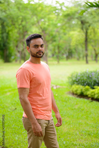 Young handsome bearded Indian man at the park