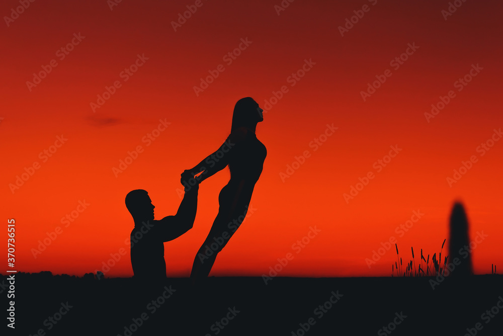 couple of people jointly perform a stretching and balance exercise in a yoga pose