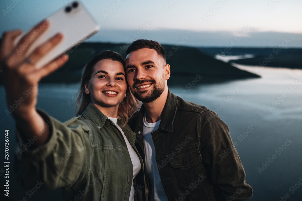 Two Young and Happy Travelers Making Selfie in Sunset Next to the Canyon Two Young and Happy Travelers Making Selfie in Sunset Next to the Canyon