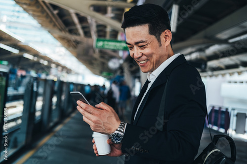 Canvas Print Business man looking phone at train station stock photo