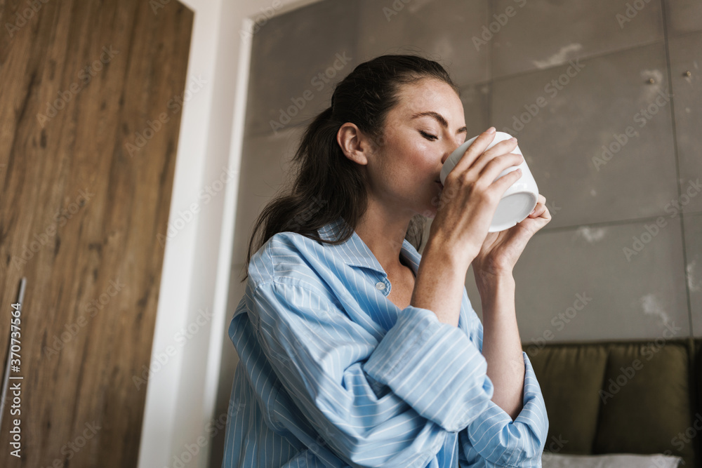 Optimistic pleased girl indoors at home drinking coffee Optimistic pleased girl indoors at home drinking coffee