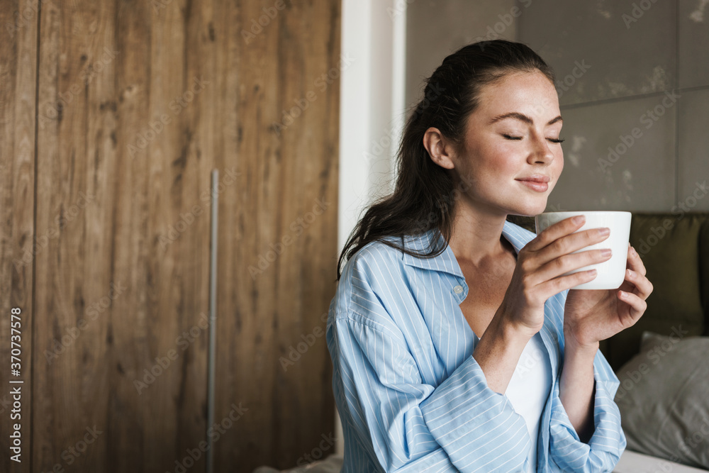 Optimistic pleased girl indoors at home drinking coffee Optimistic pleased girl indoors at home drinking coffee