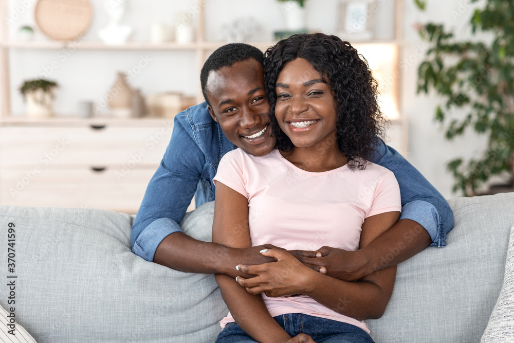 Beautiful black couple cuddling on sofa at home