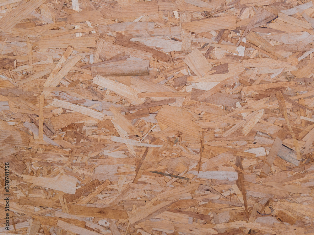 The textured surface of a wooden OSB board in natural light. Background image.