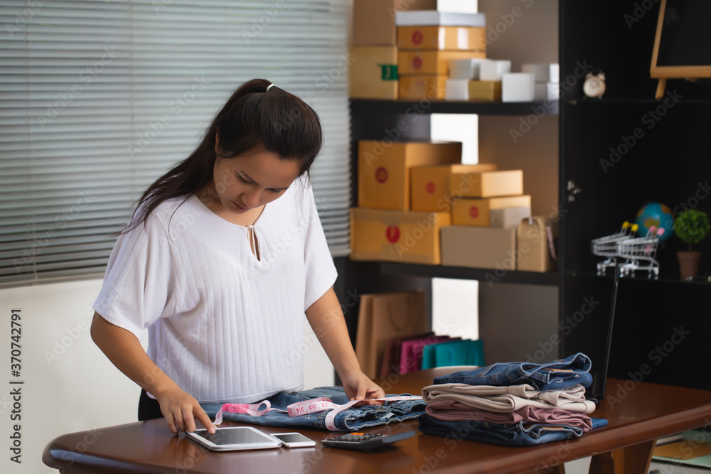 Asian woman seller are measuring trouser sizes according to their customers' orders through online shopping. Asian woman seller are measuring trouser sizes according to their customers' orders through online shopping.