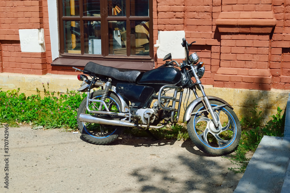 black motorcycle parked near an old building with a brown brick wall