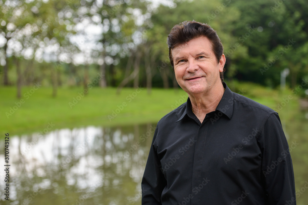 Portrait of happy mature handsome businessman relaxing at the park Portrait of happy mature handsome businessman relaxing at the park