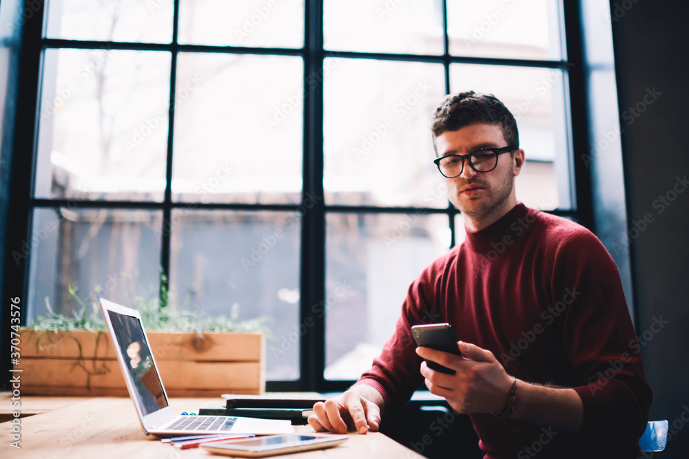 Hipster guy using application on cellular indoors Hipster guy using application on cellular indoors