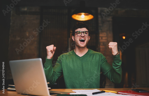 Young man watching translation on laptop computer connected to wireless internet in office photo