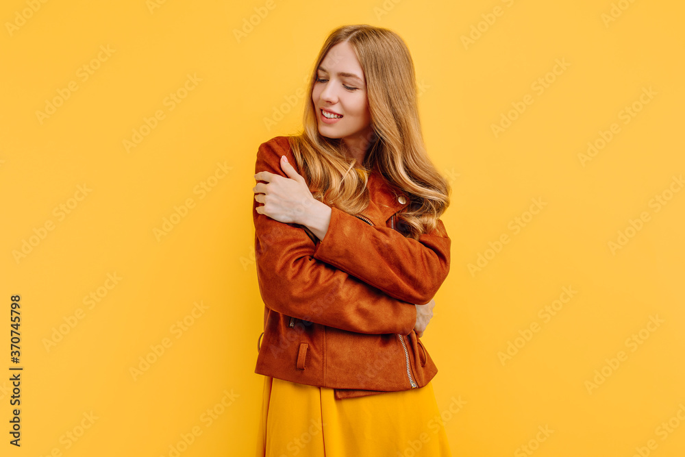 attractive, thoughtful, dreamy girl in a bright yellow dress and autumn jacket poses on an yellow background. The concept of autumn attractive, thoughtful, dreamy girl in a bright yellow dress and autumn jacket poses on an yellow background. The concept of autumn