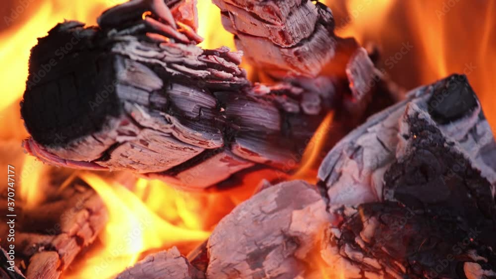 Closeup view 4k video footage of burning organic wood isolated on black background. Bright fire flames and texture of burned wooden logs.