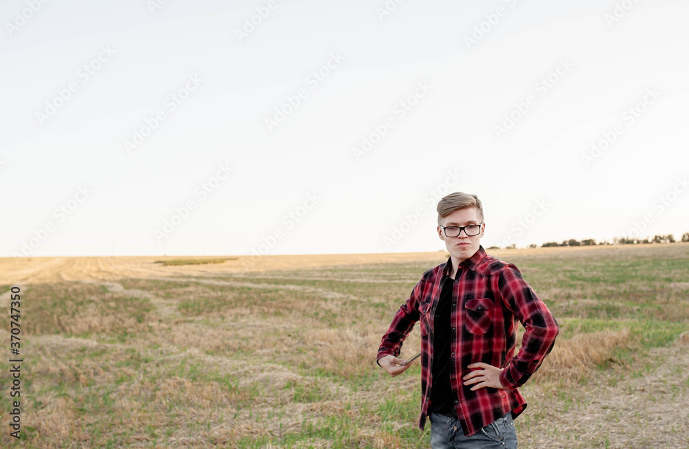 
young farmer stands on a cut field with a tablet in hand, agriculture management concept