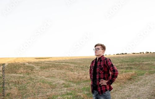 young farmer stands in a cut field, agriculture management concept