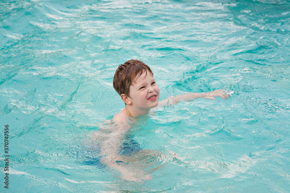 Happy preschool boy playing in the swimming pool