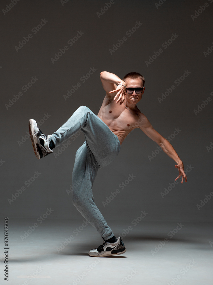 Cool guy breakdancer in sunglasses dancing hip-hop without shirt in studio. Dance school poster. Break dance lessons