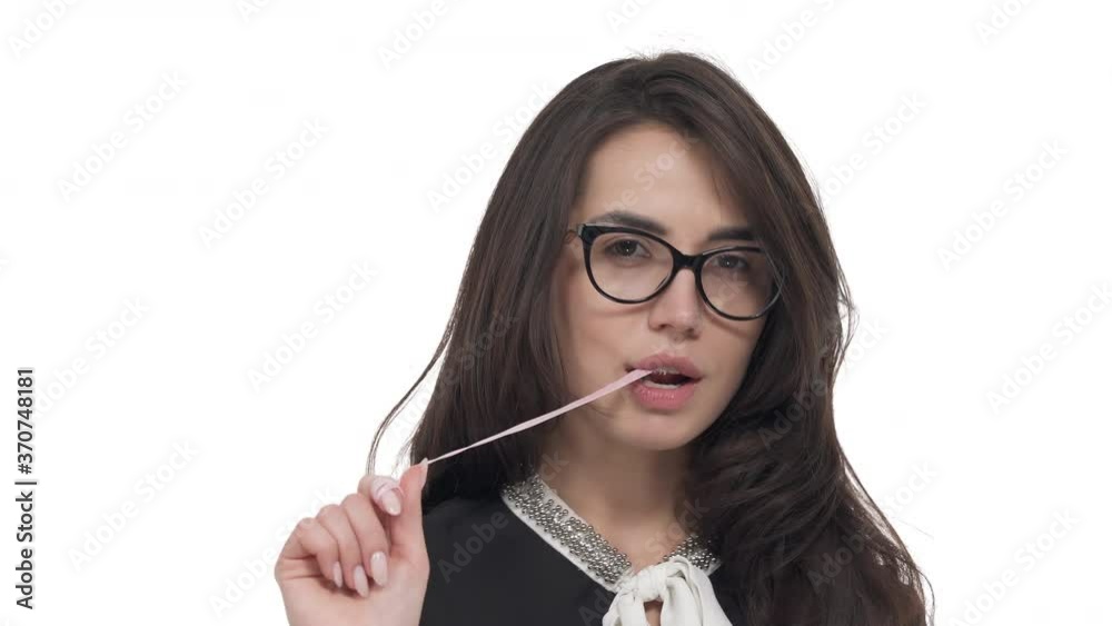 Portrait of young Caucasian woman in glasses chewing bubble gum and stretching it from mouth. Isolated on white background Portrait of young Caucasian woman in glasses chewing bubble gum and stretching it from mouth. Isolated on white background