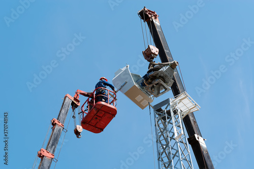 Workers on the aerial platform with the help of a crane carry out the installation of the wind generator. Russia, Orenburg region