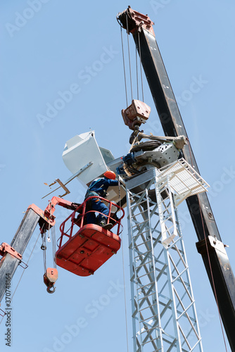 Workers on the aerial platform with the help of a crane carry out the installation of the wind generator. Russia, Orenburg region