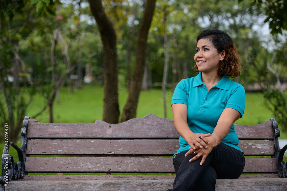 Happy mature beautiful Asian woman relaxing at the park Happy mature beautiful Asian woman relaxing at the park