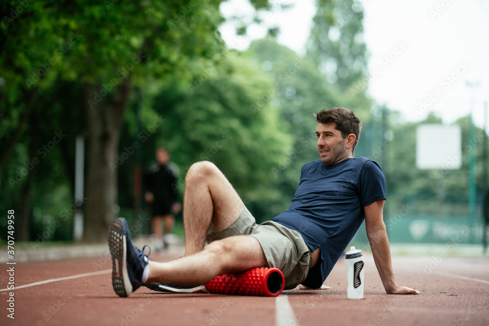 Man foam rolling. Athlete stretches using a foam roller.. Man foam rolling. Athlete stretches using a foam roller..