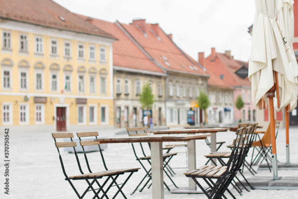 Empty wooden table with chairs in front of cafe in old city center.