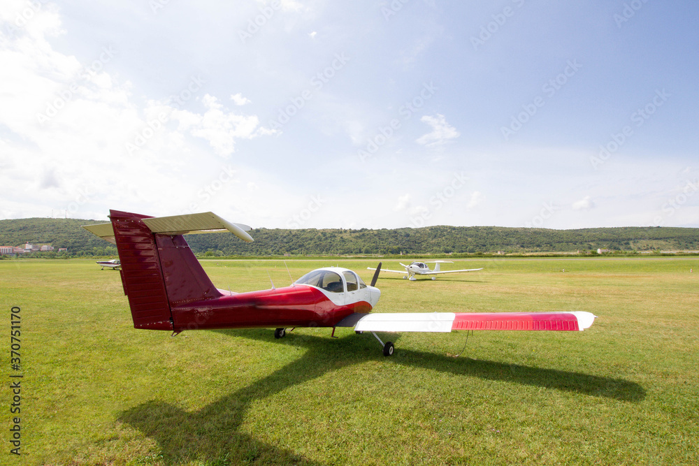 Light aircraft parked on the grass next to a small airport.