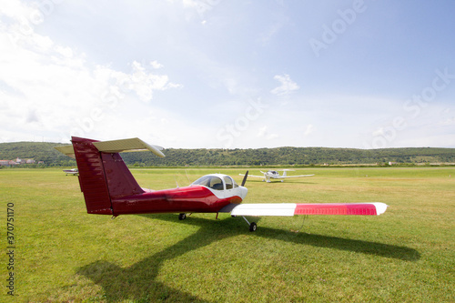 Light aircraft parked on the grass next to a small airport. photo