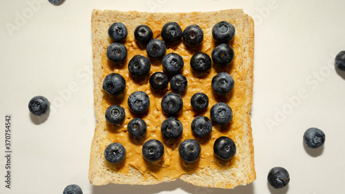 Toast with peanut butter and blueberries on a white plate. View from above