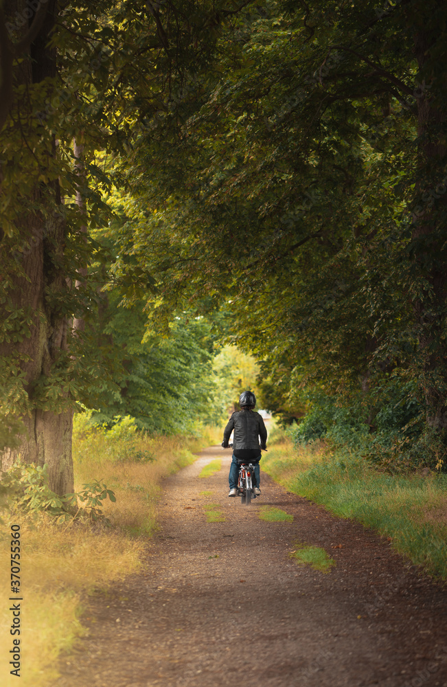 Exploring the forest by moped, lonely journey by motorbike through the forest, guy on moped driving down a dirt road Exploring the forest by moped, lonely journey by motorbike through the forest, guy on moped driving down a dirt road