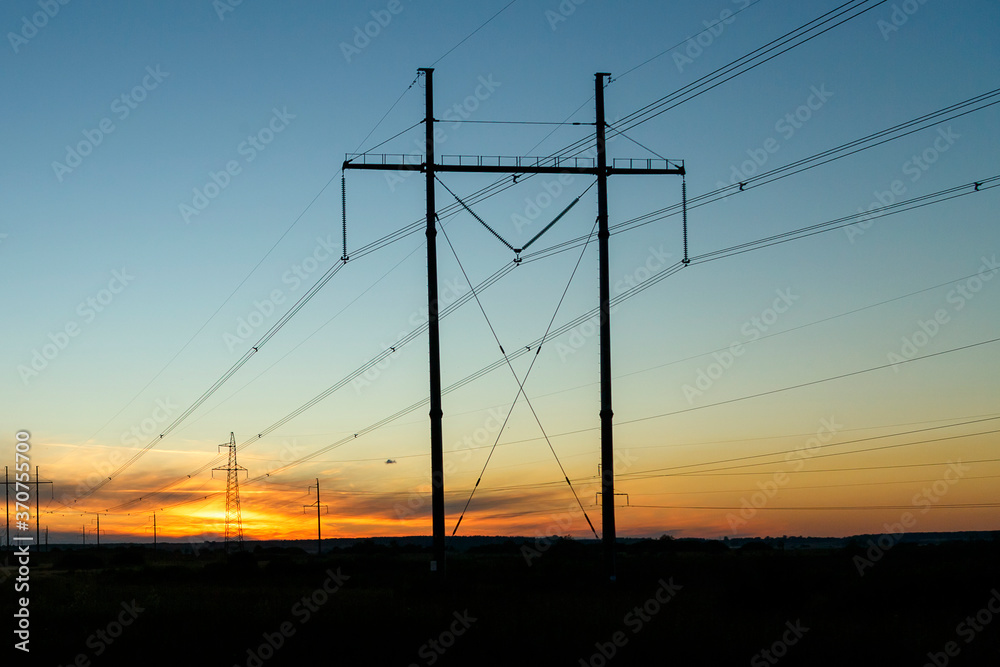 High voltage power lines in the light of the setting sun.