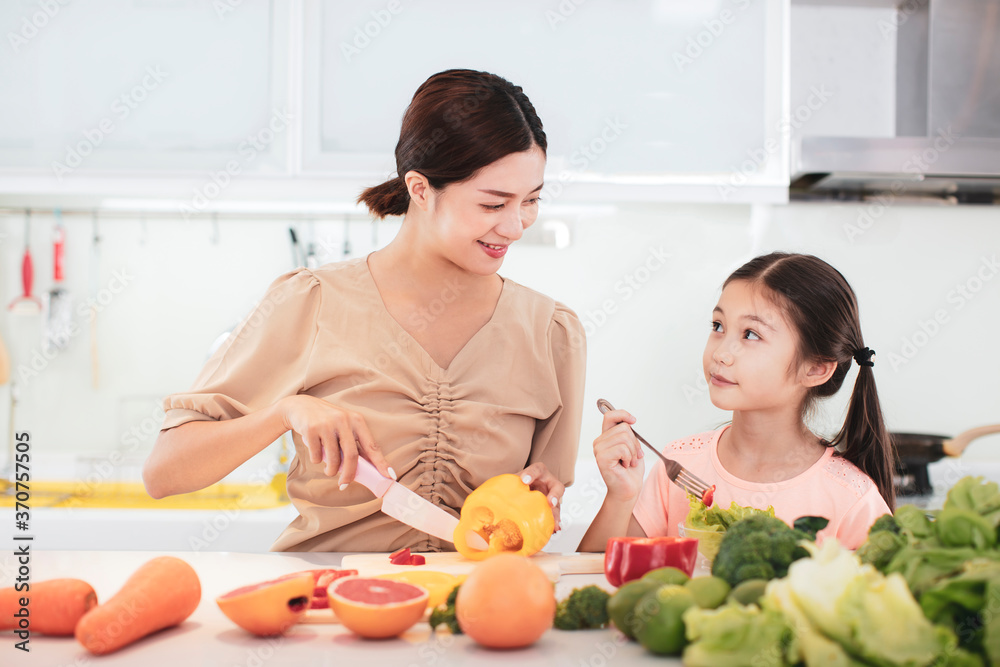 happy Mother and child daughter  eating the vegetables and fruit