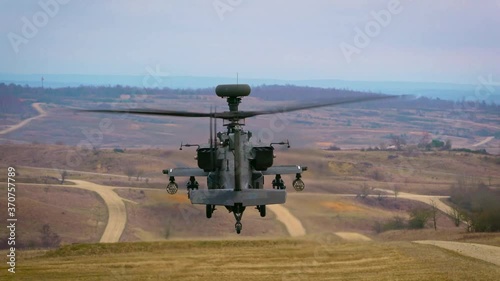 A AH-64 Apache helicopter hovering over ground