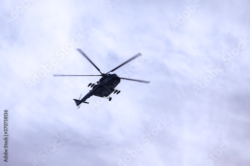 Military helicopter of Russian armed forces flies in sky with textural clouds. Day of Navy of Russia. Naval parade. Holidays of Saint Petersburg, Russia. Rehearsal of parade