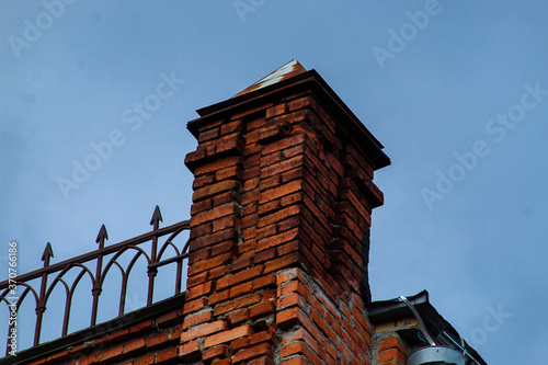 An old brick tower on the roof, an old red-brick structure. The fence on the roof