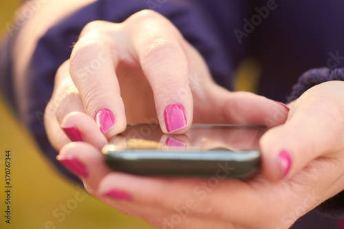 Close-up of female hands holding a modern smartphone. © astrosystem