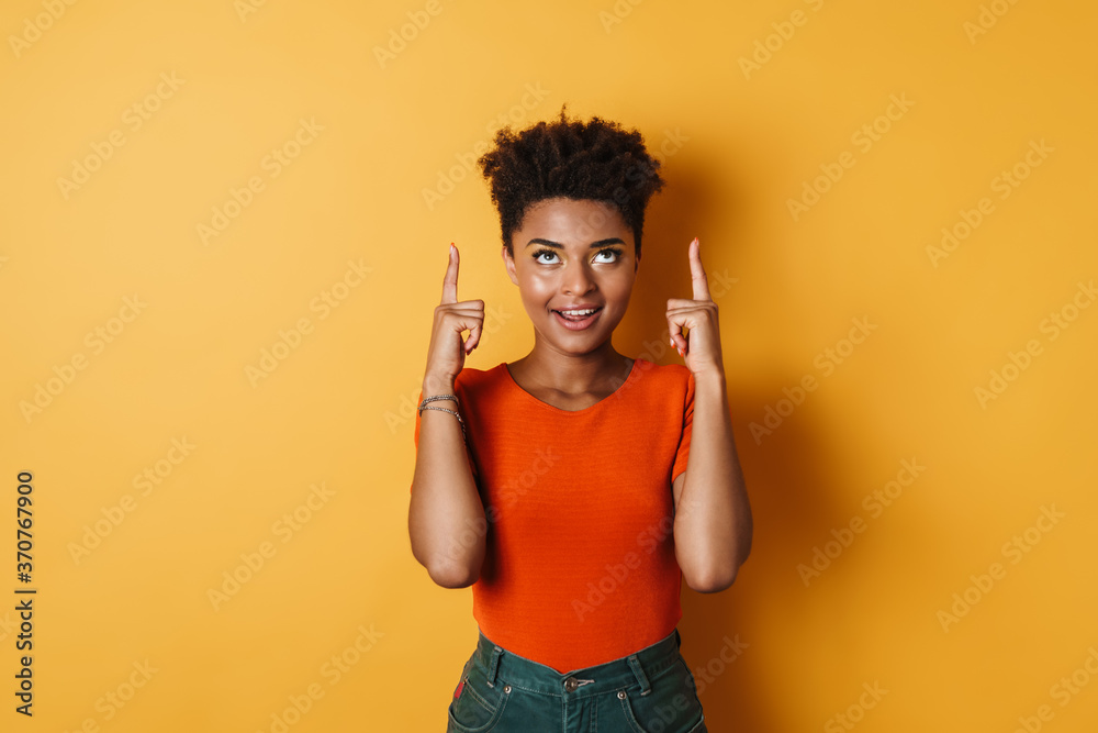 Image of african american woman pointing fingers upward and smiling