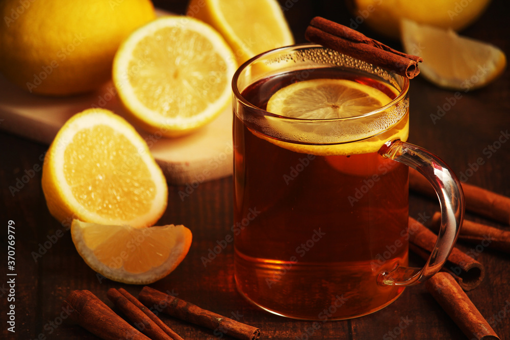 A mug with hot tea with lemons and cinnamon sticks A mug with hot tea with lemons and cinnamon sticks