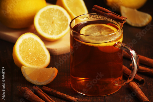 A mug with hot tea with lemons and cinnamon sticks 
