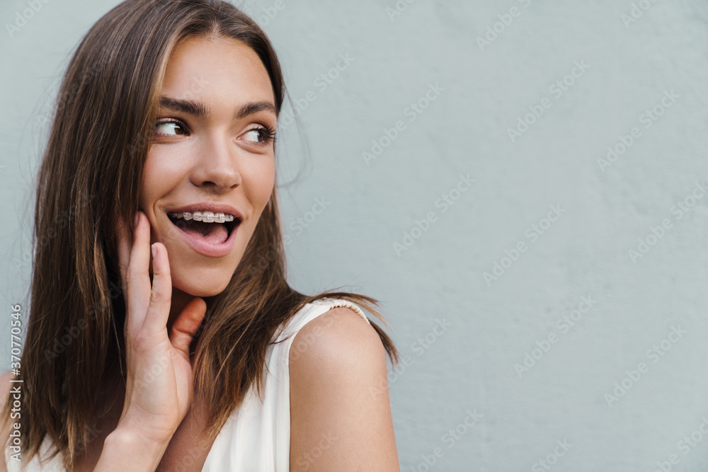Fototapeta premium Woman posing over grey wall while looking aside.