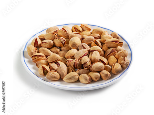 salted pistachios in a shell on a white saucer with a blue border, isolated on a white background