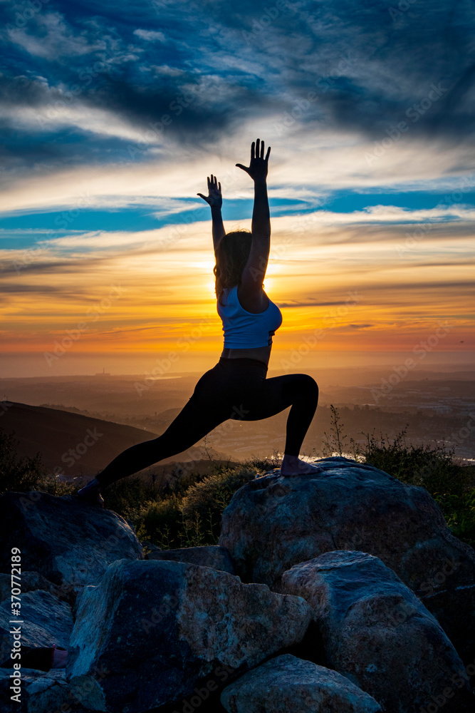 Silhouette of a woman doing yoga on mountain top in California