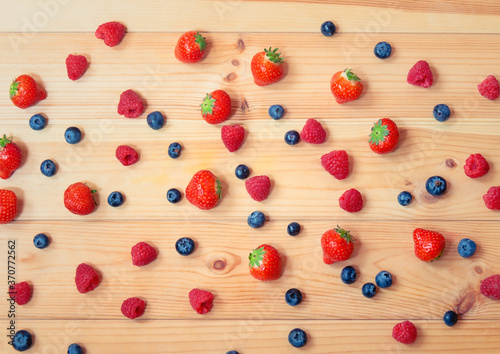 Strawberries, blueberries and raspberries on wooden background