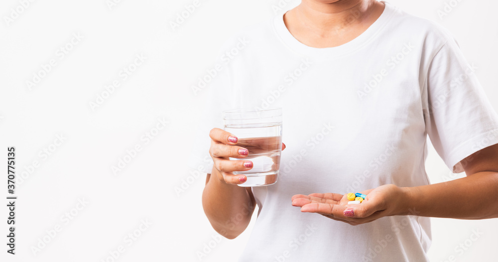 Closeup young Asian woman hold pill drugs in hand ready take medicines with a glass of water, studio shot isolated on white background, Healthcare and medical pharmacy concept Closeup young Asian woman hold pill drugs in hand ready take medicines with a glass of water, studio shot isolated on white background, Healthcare and medical pharmacy concept