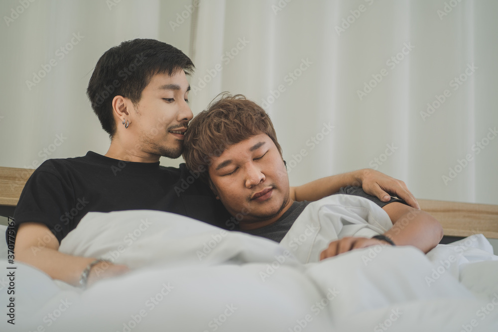 Happy gay couple lying on bed at home Happy gay couple lying on bed at home