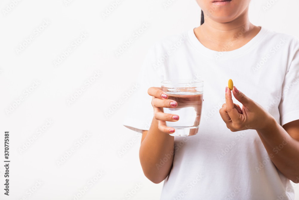 Closeup young Asian woman hold fish oil vitamin drugs in hand ready take medicines with a glass of water, studio shot isolated on white background, Healthcare and medical pharmacy concept Closeup young Asian woman hold fish oil vitamin drugs in hand ready take medicines with a glass of water, studio shot isolated on white background, Healthcare and medical pharmacy concept