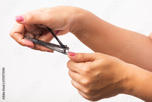 Close up young Asian woman have tool cutting nails fingernails on finger using a nail clipper. Female using tweezers by herself  studio shot isolated on white background  Healthcare concept