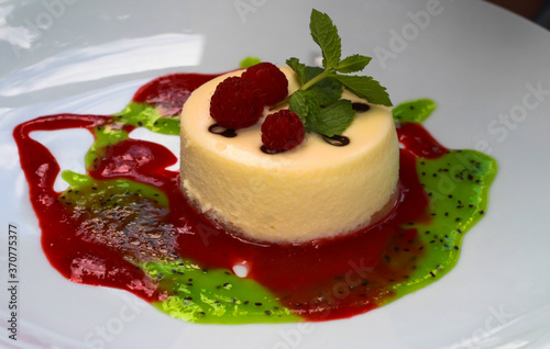 Cheesecake with fresh raspberries. Cottage cheese dessert with raspberry jam and kiwi on a white plate.